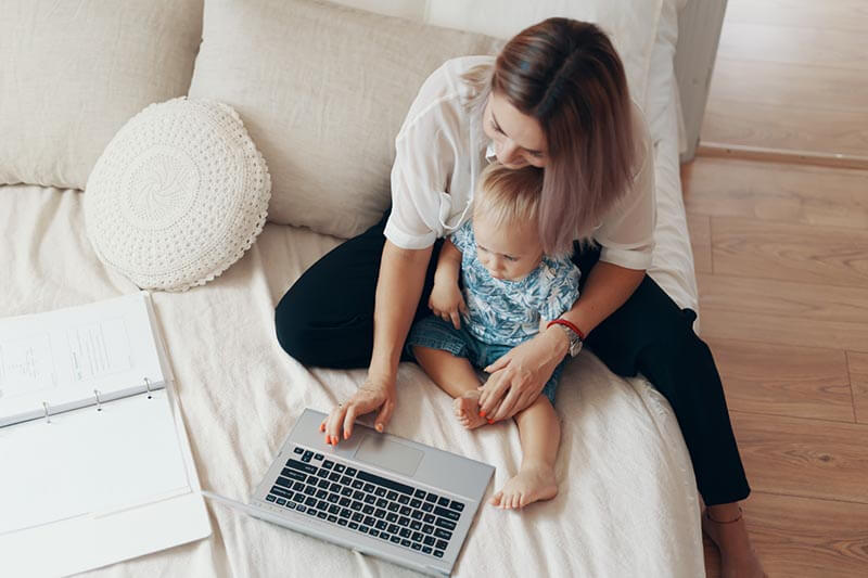 Mulher trabalhando em casa com computador e filho